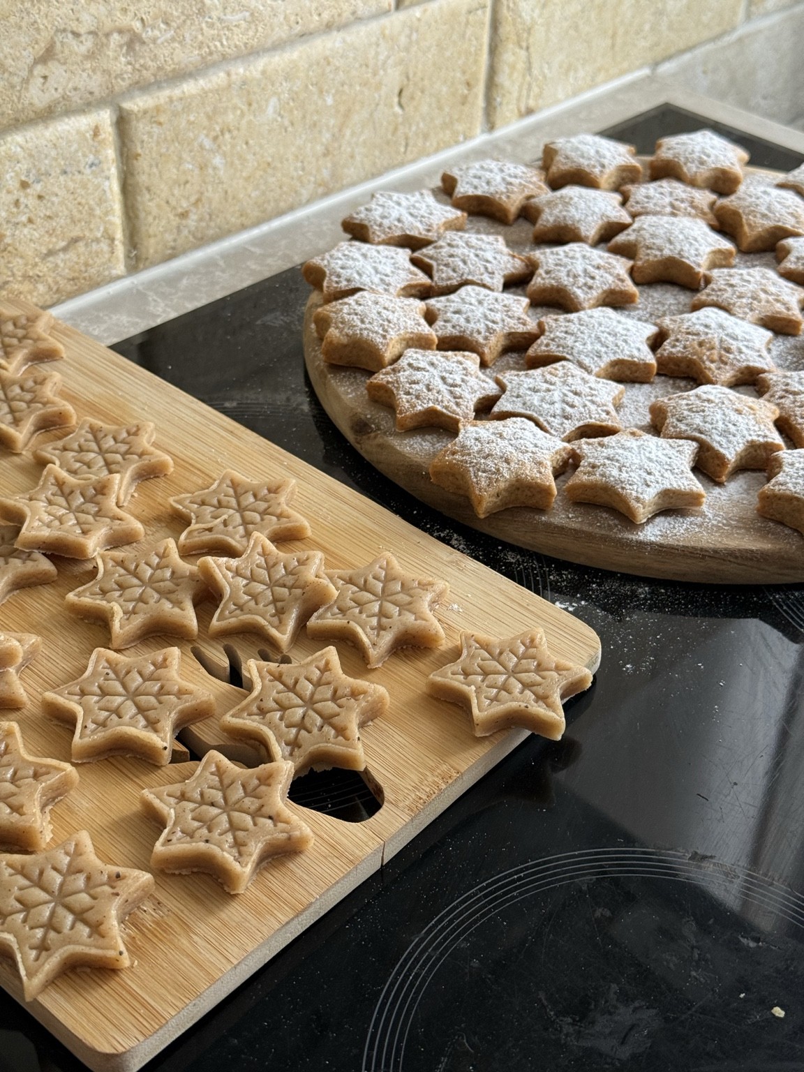 Steluțe din aluat decupat, înainte de coacere, alături de turta dulce coaptă și pudrată